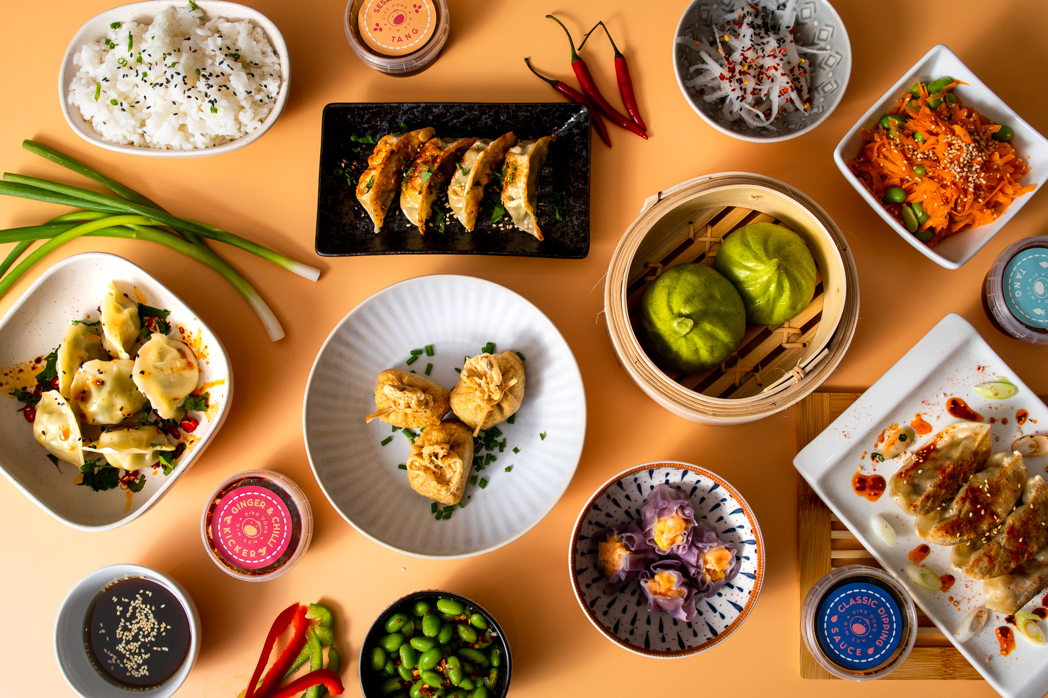 Selection of dim sum dishes including dumplings, buns, rice and edamame arranged for a shared Lunar New Year meal at home.
